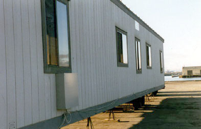 Side view of office trailer on stands, with phone box on side.